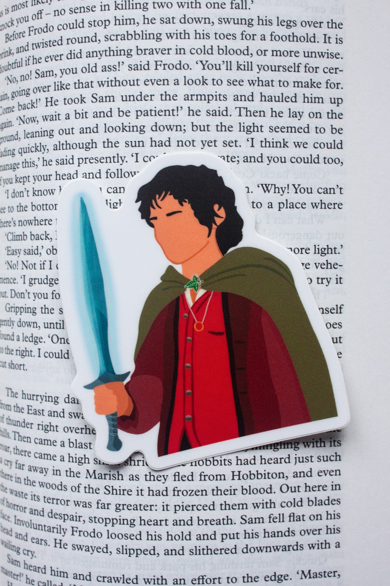 Frodo Baggins sticker from The Lord of the Rings, featuring the brave hobbit holding the One Ring with a determined expression. Perfect for fans of Frodo and Tolkien’s epic fantasy.