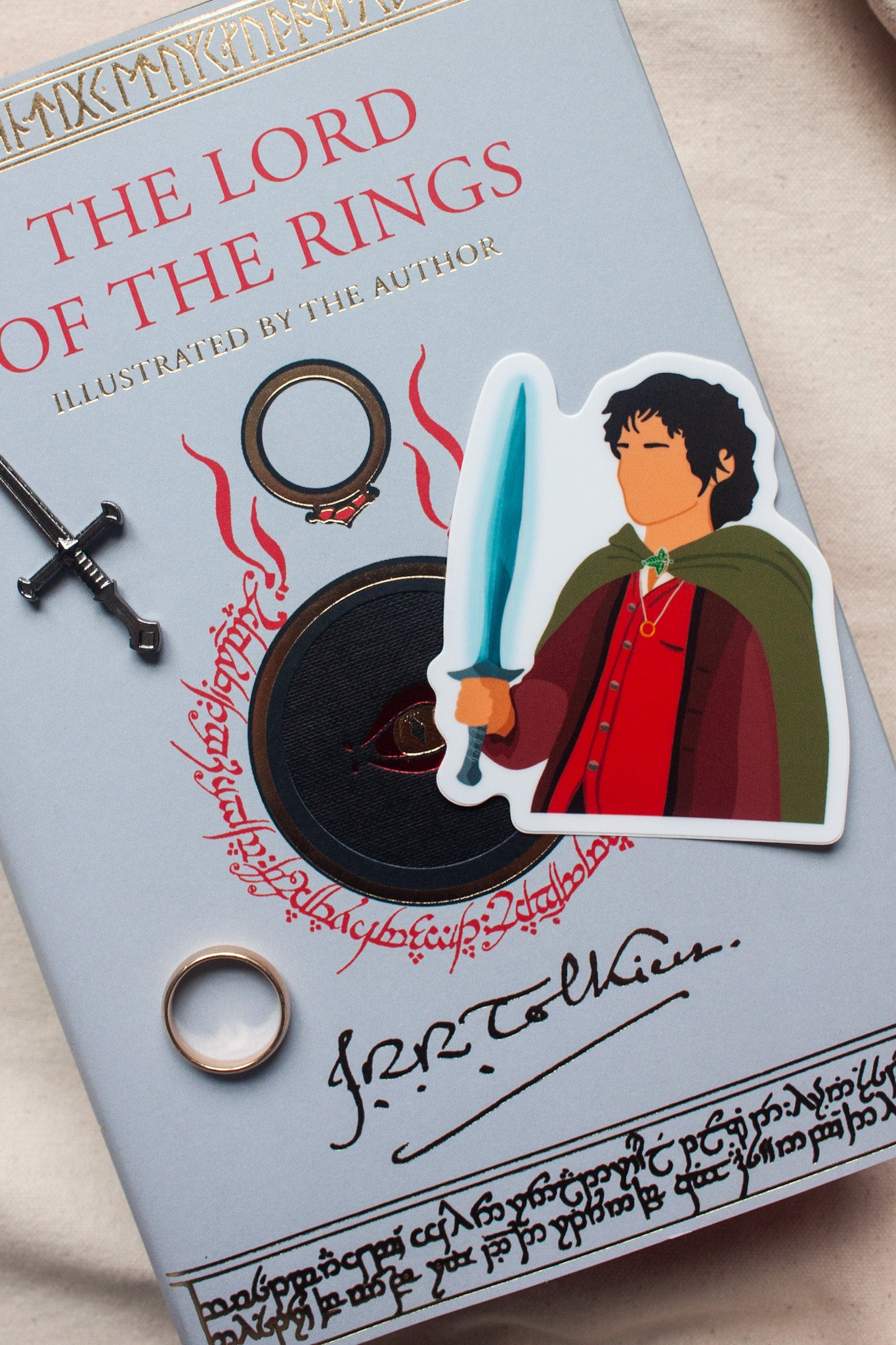 Frodo Baggins sticker from The Lord of the Rings, featuring the brave hobbit holding the One Ring with a determined expression. Perfect for fans of Frodo and Tolkien’s epic fantasy.